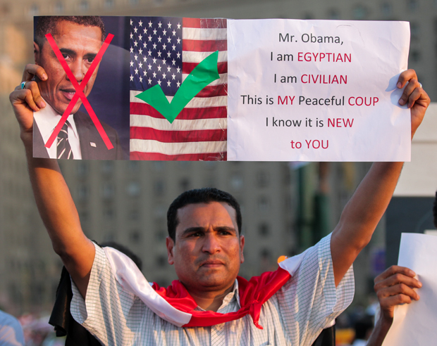An Egyptian protestor holds a sign showing the anger of some Egyptian people towards the American government. (Photo: Amr Abdel-Hadi / Demotix)