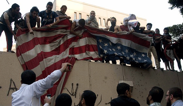 A blackened flag inscribed with the Muslim profession of belief, "There is no God, but God and Mohammed is the prophet of God," is raised on the wall of the US Embassy by protesters during a demonstration against a film. Nameer Galal | Demotix 