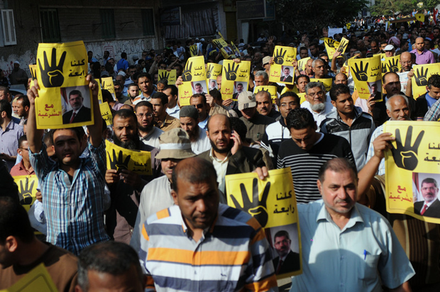 Supporters of Egypt's ousted President Mohammed Morsi in Helwan District raise his poster and their hands with four raised fingers, which has become a symbol of the Rabaah al-Adawiya mosque. (Nameer Galal / Demotix)