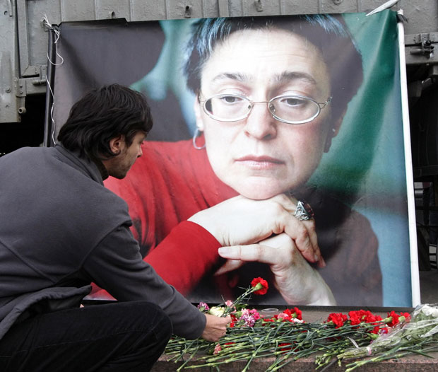 A man lays flowers near the picture of murdered journalist Anna Politkovskaya, during a rally in Moscow, Russia, 7 October 2009. CREDIT: EPA / Alamy Stock Photo 