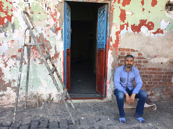 Cumali, sitting in front of his evacuated house, did not want to leave Sur. He has been moved to temporary housing on a road that has not yet been demolished. Cumali says, "I was born in Sur, I grew up, got married, let us relax, I want to die in Sur."